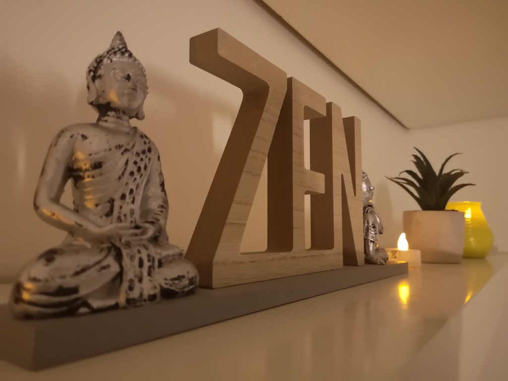 Zen sign with candles, plants and Buddha figurine.   